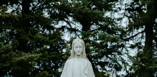 Eine Marienstatue vor dunkelgrünen Tannenzweigen