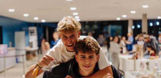 Zwei Teenager lachen in die Kamera.