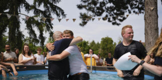 Pulsechurch: Eine Gemeinde am Herzen Gottes Bei einer Taufe der pulsechurch unter freiem Himmel in einem Pool umarmen sich zwei Männer.