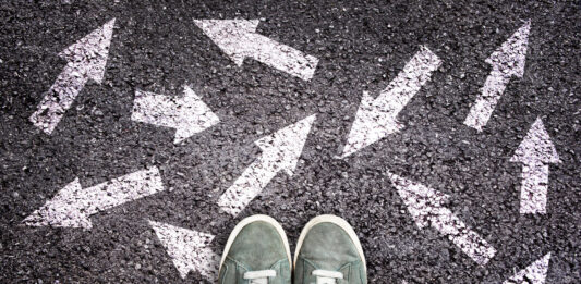 Asphalt mit vielen Pfeilen und einem Paar Schuhen