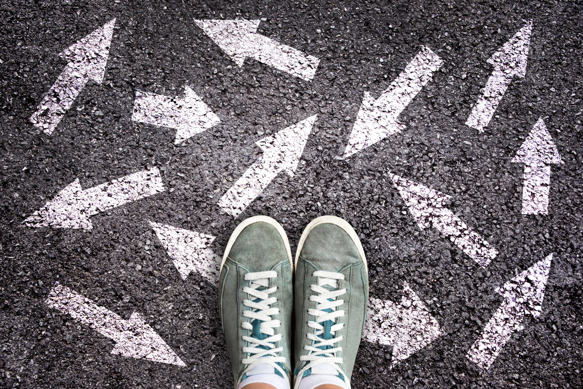 Asphalt mit vielen Pfeilen und einem Paar Schuhen