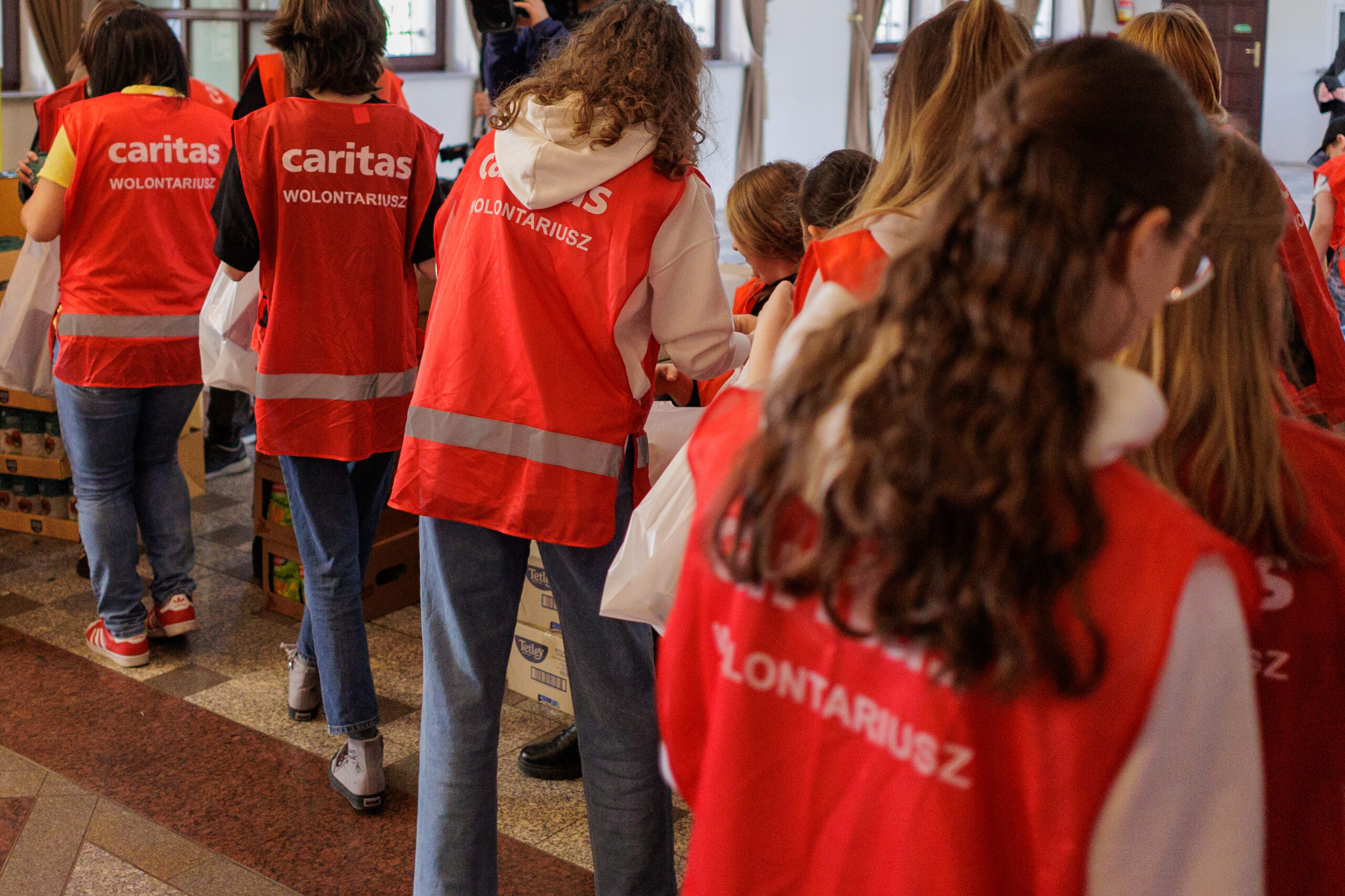 Caritas Helfer mit orangenen Westen packen Taschen mit Lebensmitteln.