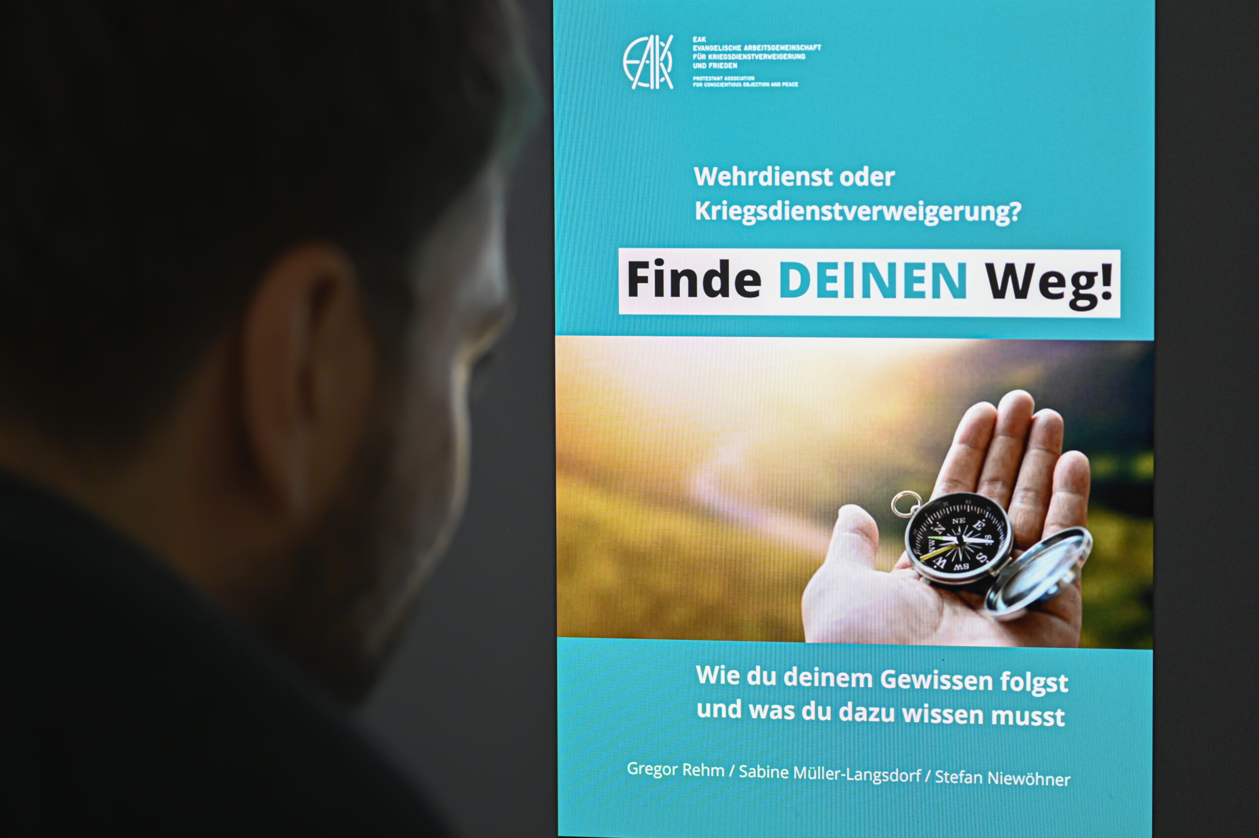 Ein Mann blickt in eine Friedensbroschüre der Kirche