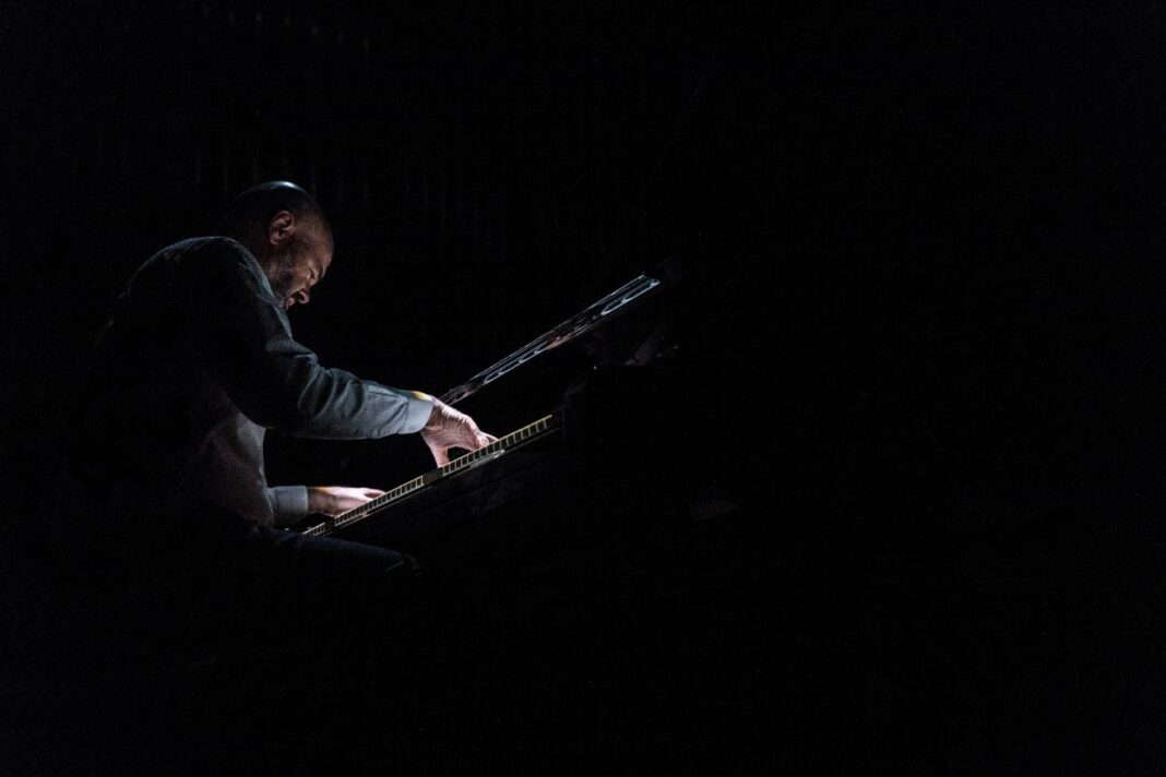 Ein Mann spielt im Dunkeln Klavier.