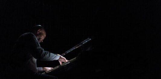 Ein Mann spielt im Dunkeln Klavier.