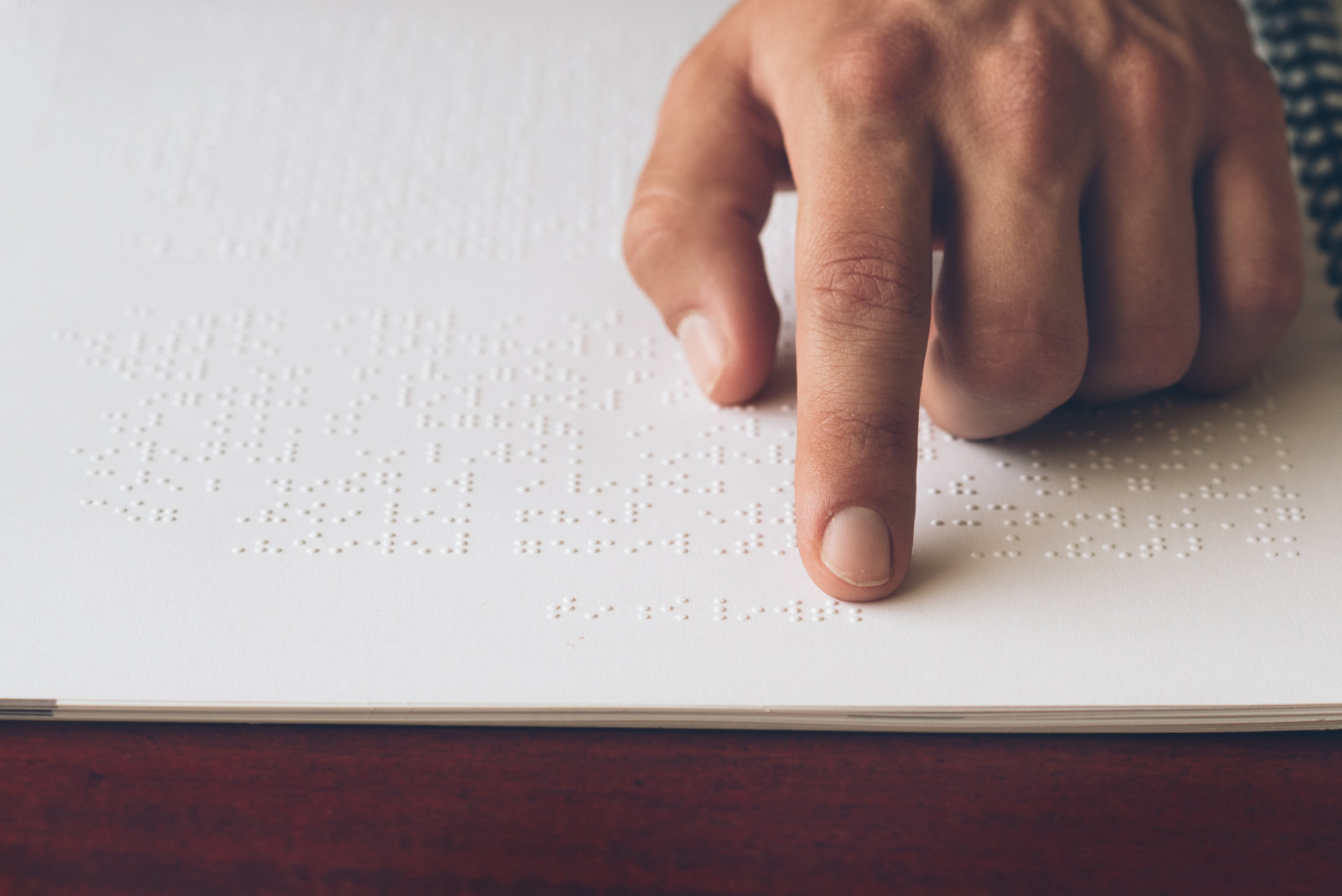 Person liest Buch mit Blindenschrift