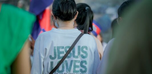 Eine Frau mit einem "Jesus loves you" Tshirt